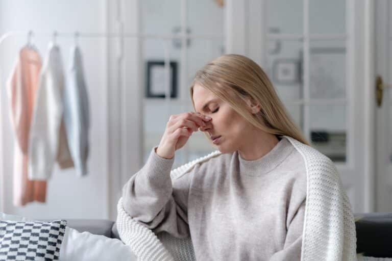 Woman holding her nose in discomfort from a polyp