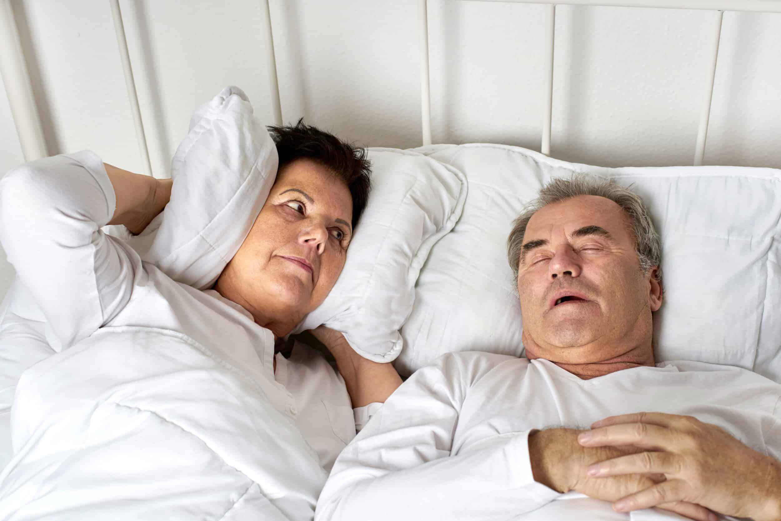 Woman trying to sleep is annoyed by her husband's snoring